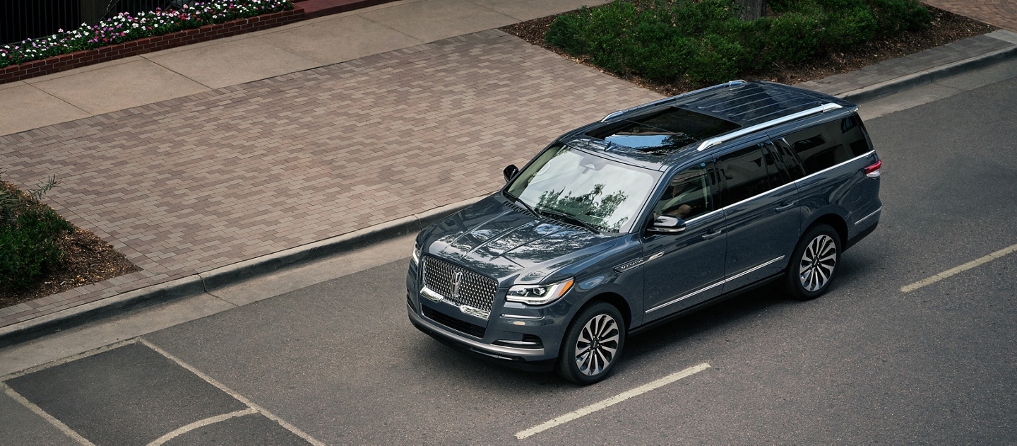 A 2023 Lincoln Navigator® SUV is being driven toward a speed bump on a downtown street