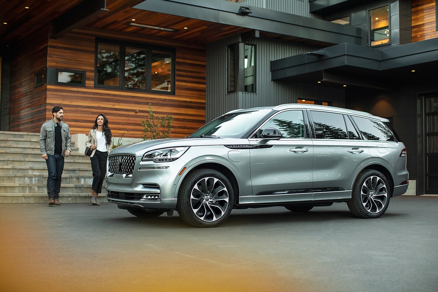 Two people are shown approaching a parked Lincoln Aviator