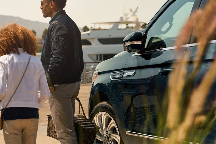 A little girl and dad walk away from a 2024 Lincoln Navigator SUV with its sideview mirrors folded