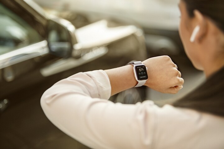 A woman is outside and interacts with the Lincoln Way App® on her smartwatch as she approaches her Lincoln