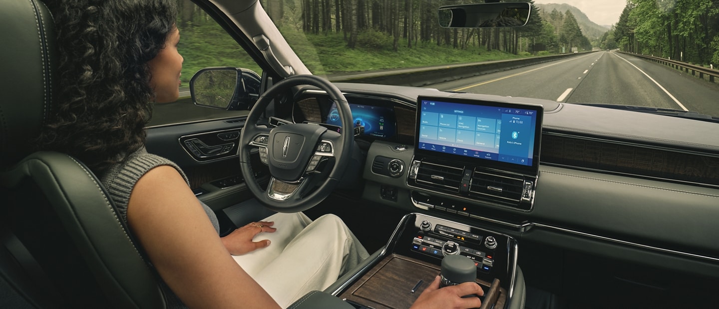A driver of a 2024 Lincoln Navigator SUV relaxes with hands-free driving technology engaged ADAPTIVE SUSPENSION