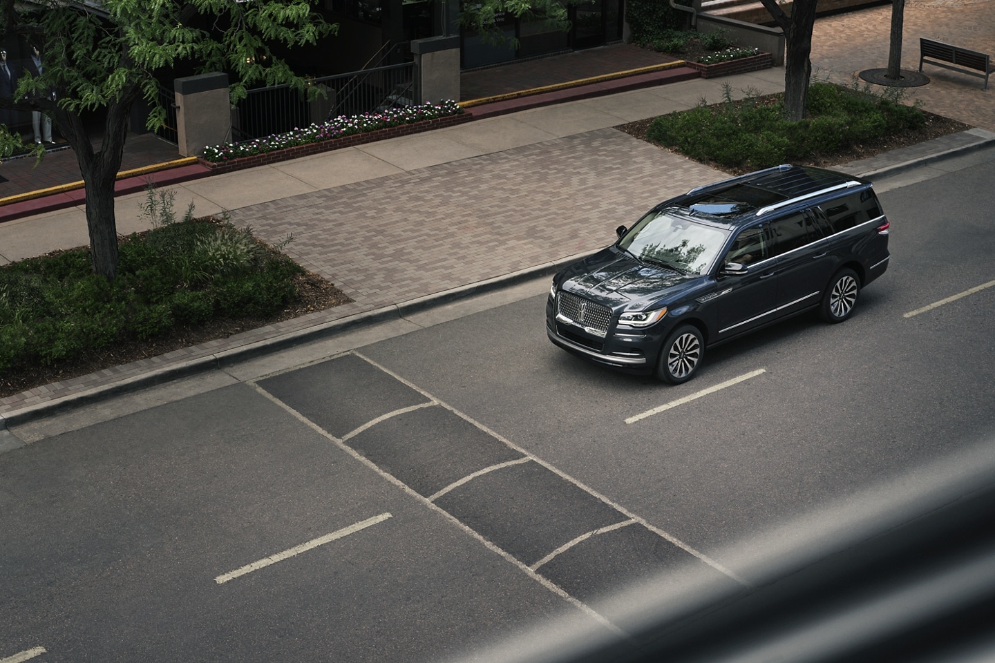 A 2024 Lincoln Navigator SUV is being driven toward a speed bump on a downtown street