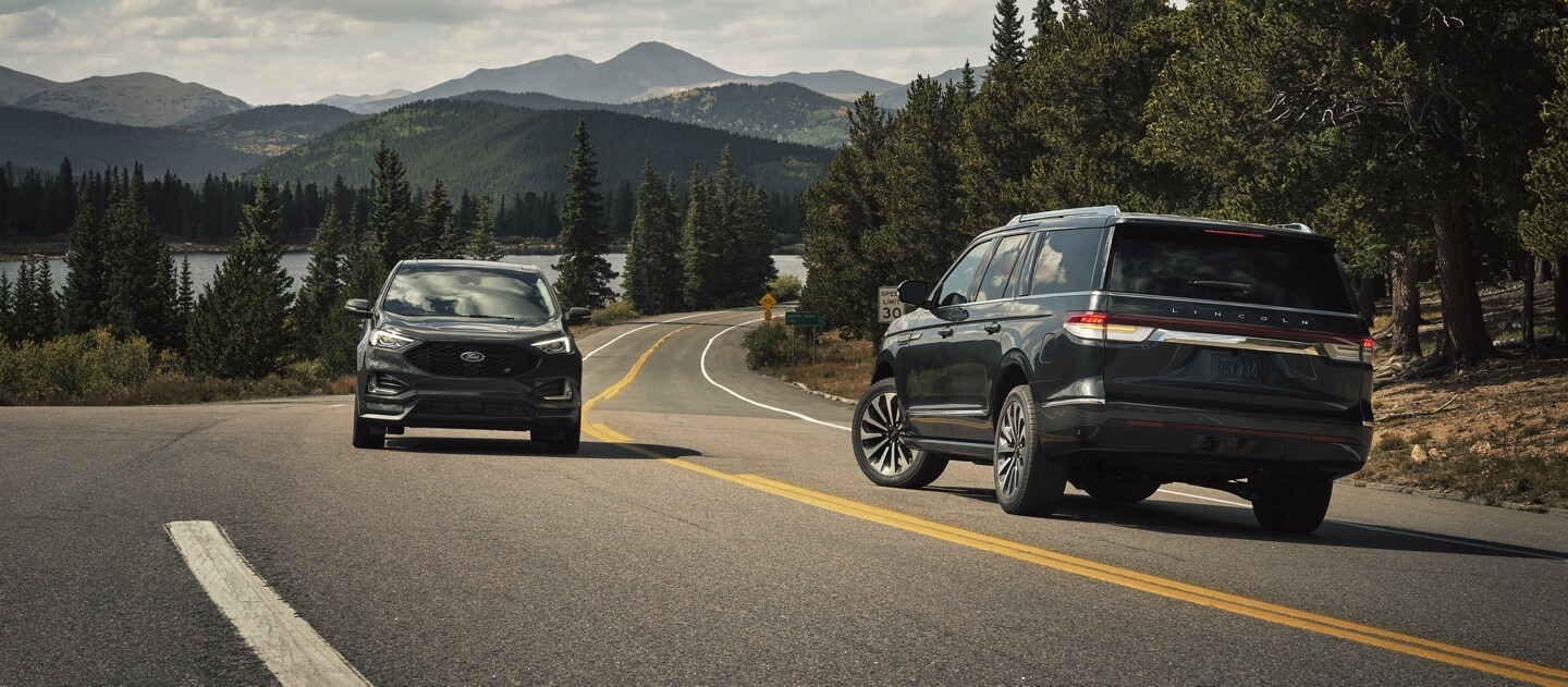 A 2024 Lincoln Navigator SUV is making a left turn as another vehicle approaches from the other lane