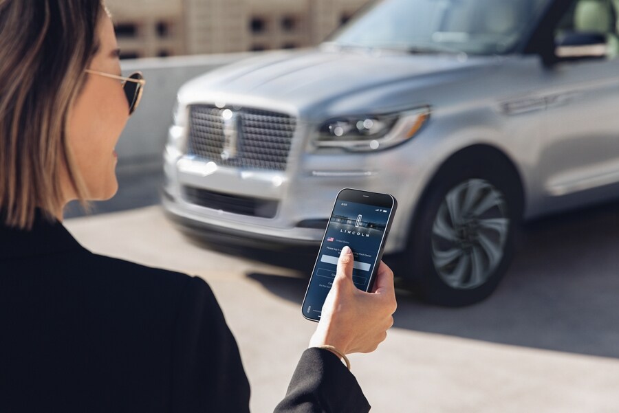 A woman interacts with the Lincoln Way App on her smartphone as she approaches her Lincoln