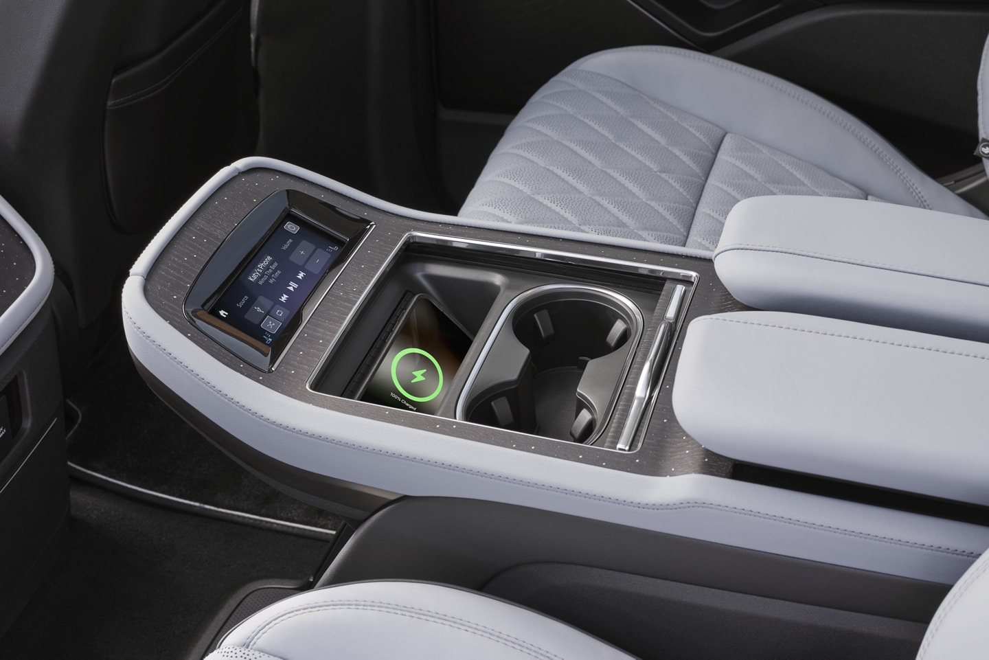 A phone charges on a wireless charging pad in the second row console of a 2025 Lincoln Black Label Navigator® SUV