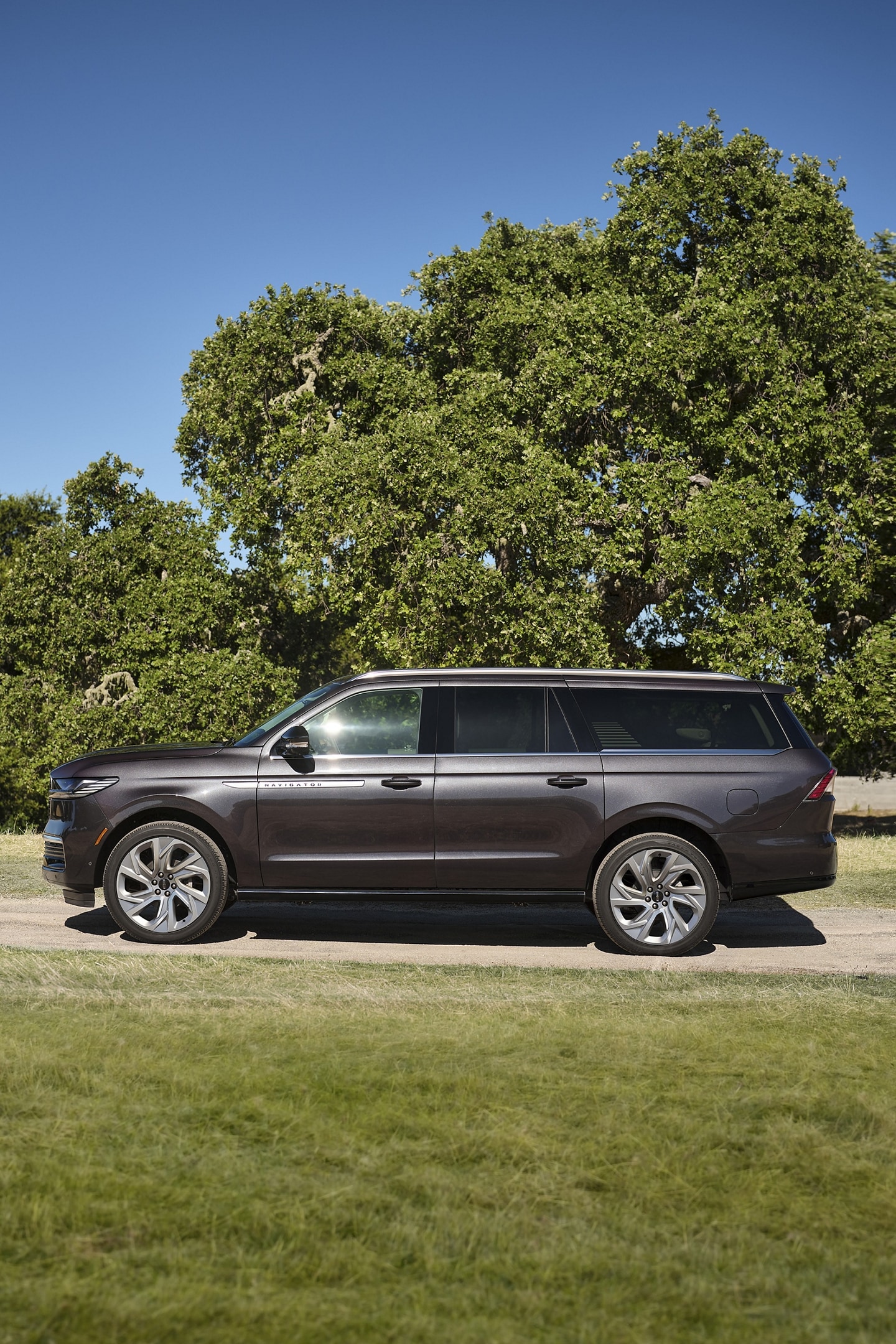 A 2025 Lincoln Navigator® with the long wheelbase is parked in a tree line road