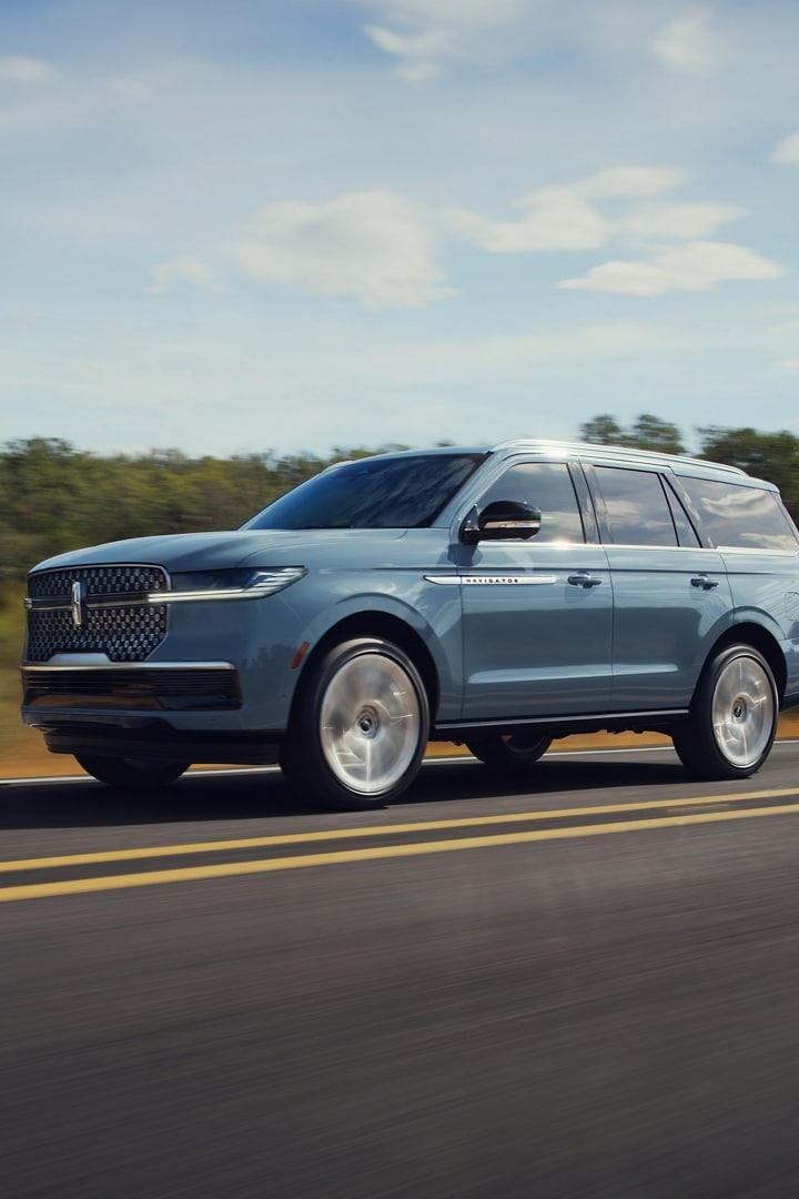 A 2025 Lincoln Navigator driving down a highway with trees in the background
