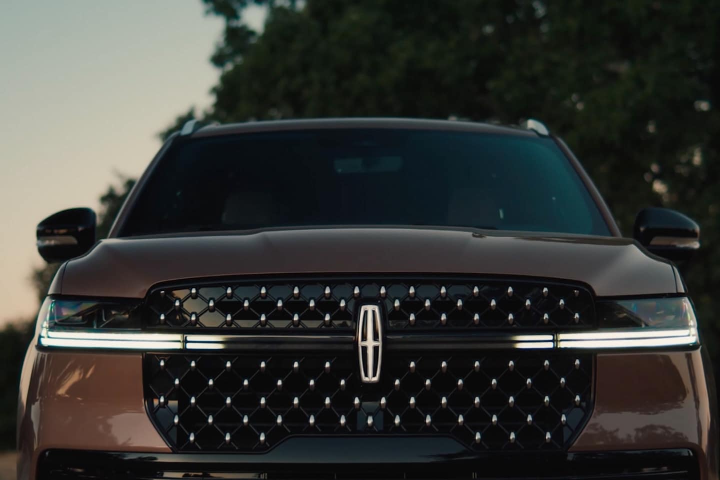 The grille of a parked 2025 Lincoln Navigator displays the lighting sequence of the Lincoln Embrace