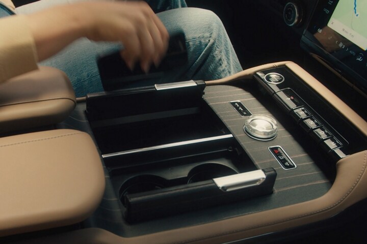 The driver of a 2025 Lincoln Black Label Navigator® reaches to place a smartphone on the wireless charging pad